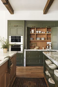 a kitchen with green cabinets and white counter tops on a rug in front of an oven