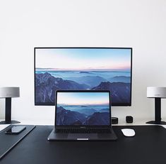 a laptop computer sitting on top of a desk next to a monitor and mouse pad