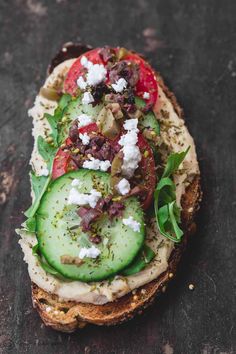 an open face sandwich with cucumber, tomatoes and feta cheese on it