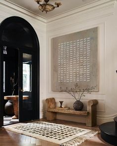 an entryway with a rug, vases and a painting on the wall above it