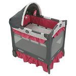 a baby crib that is red and grey with a pink bed skirt on it