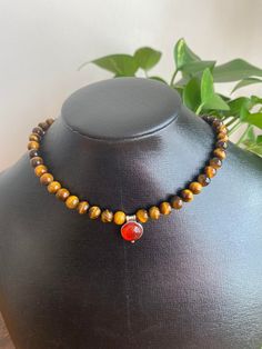 This choker is from my beauty of the Southwest Collection. A beautiful vibrant red-orange carnelian centerpiece is surrounded by tigers' eye gemstones. The necklace length is 16." Carnelian pendant is 10mm round, tiger's eye beads are 6mm each. Completely finished in sterling silver. Gift box included. Enjoy complimentary domestic shipping. The necklace will ship within 3-5 business days. Thank you, Althea Morgan-Campbell Spiritual Brown Choker As Gift, Spiritual Brown Choker Gift, Brown Gemstone Beaded Necklace, Carnelian Jewelry For Meditation In Brown, Brown Carnelian Jewelry For Meditation, Wooden Bead Jewelry, Silver Gift Box, Carnelian Pendant, My Beauty