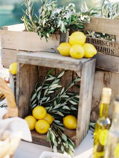 some lemons are sitting in crates on a table with other food and wine bottles