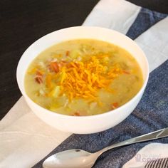 a white bowl filled with soup and cheese on top of a blue napkin next to a spoon