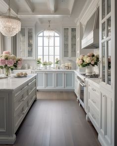 a large kitchen with white cabinets and flowers in vases on the counter top, along with an arched window