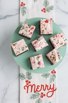 christmas brownies on a green plate with merry written in red and white frosting