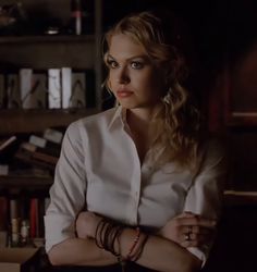 a woman standing in front of a bookshelf with her arms crossed