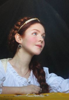 a woman with long red hair wearing a white dress and gold headband looking off into the distance