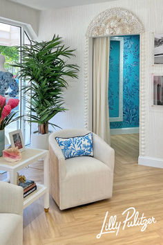 a living room filled with white furniture and blue wallpaper on the walls next to a window