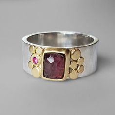 This little faceted raspberry pink tourmaline has a lovely glow that really captures its depth. A hammered faceted 8mm silver band displays this pretty pink tourmaline in an 18k yellow gold bezel with gold dot flourishes on either side and a small pink sapphire flush set accent. Size 8. Can be sized upon request. Arrives to you in a special gift box. Aura Ring, Silver Stone Ring, Gold Dot, Unusual Rings, Raspberry Pink, Gold Dots, Deep Pink, Metal Work, Pretty Pink