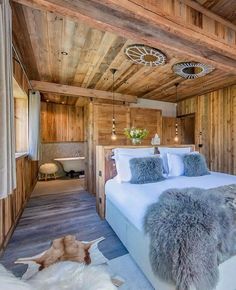 a bedroom with wood paneling and white bedding in the center is an animal - print rug on the floor