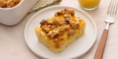 a piece of casserole on a white plate next to a glass of orange juice