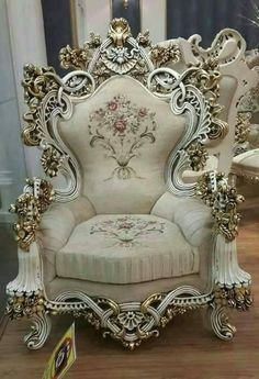 an ornate white chair sitting on top of a wooden floor