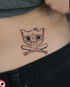 a woman's stomach with a cat and crossed baseball bats tattoo on her belly