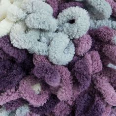 a pile of purple and white crocheted teddy bears