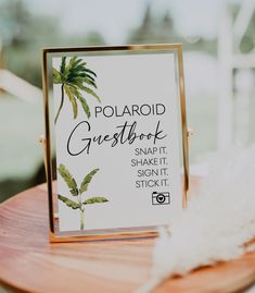 a polaroid guest book sitting on top of a wooden table next to a white feather