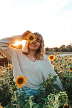 a woman standing in a field of sunflowers with her hands on her head