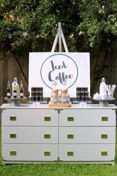 a white dresser sitting on top of a grass covered field next to a sign that says iced coffee