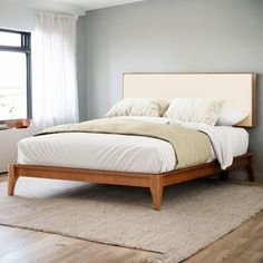 a bed sitting on top of a wooden floor next to a window