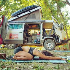 a woman laying on the ground in front of a camper van with its doors open