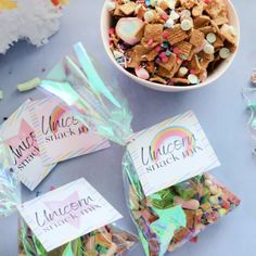 there are three bags of unicorn snack mix next to a bowl of marshmallows