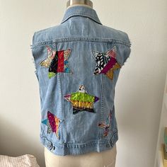 a woman's jean jacket with colorful patches and fish on the back, sitting on a mannequin