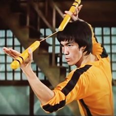 a young man holding a baseball bat over his head and wearing an orange shirt with black stripes