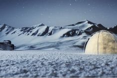 a snow covered field with mountains in the background and an oval object on the ground