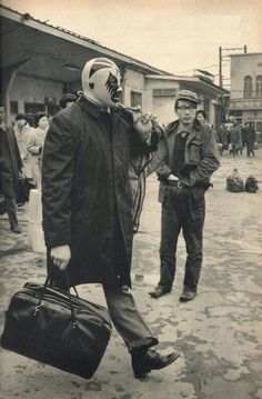 an old photo of two men walking down the street with luggage on their feet and one man holding a bag