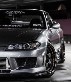 the front end of a silver car parked in a garage