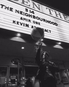 a woman is playing volleyball in front of the marquee for the neighborhood theater