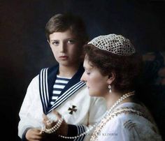 an old photo of two people dressed in traditional clothing, one wearing a tiara and the other wearing pearls