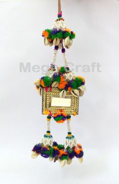 a colorful birdhouse ornament hanging from a hook on a white background with a name plate