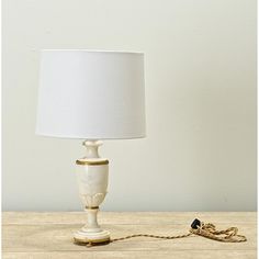 a white lamp sitting on top of a wooden table next to a light bulb and a cord