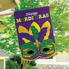 a happy mardi gras banner hanging from a tree in front of a house