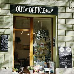 the outside of an office building with signs on it's windows and plants in front