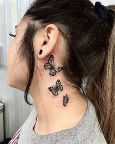 a woman's neck with three butterflies on her left side and behind the ear