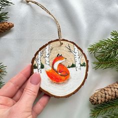 a hand holding a small ornament with a red fox on it