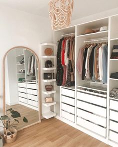 an organized closet with white drawers and open shelving units, mirror on the wall