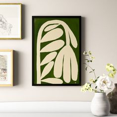 a white vase filled with flowers next to pictures on the wall