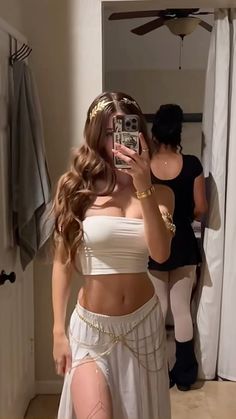 a woman is taking a selfie in the mirror while wearing a white skirt and crop top