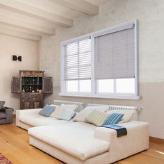 a living room with a white couch and wooden floors in front of a large window