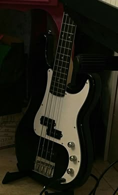 a black and white bass guitar sitting on top of a floor next to a keyboard