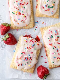 strawberry shortbreads with white frosting and sprinkles on parchment paper