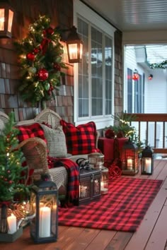 a porch decorated for christmas with plaid pillows and candles