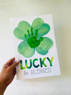 a hand holding up a card that says lucky and is painted with green paint on it