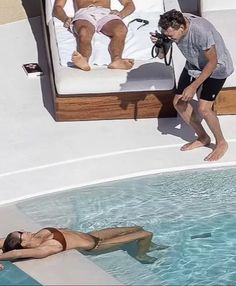 a man standing next to a woman in a swimming pool while another person takes a photo