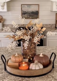 a tray with candles, flowers and pumpkins on it in the middle of a kitchen