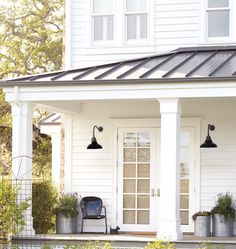 a white house with two black lamps on the front porch