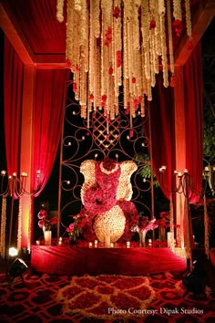 an elaborately decorated stage with flowers, candles and decorations for a wedding ceremony at night